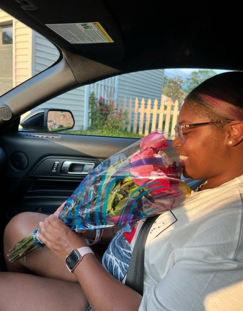 A widow smiling while holding a bouquet of roses in the car, honoring Mother’s Day while grieving and learning to celebrate love.
