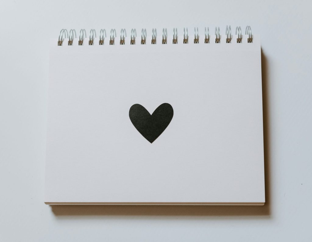 Minimalist white notebook with a black heart on the cover, symbolizing personal letters and reflections from LaNolaMom